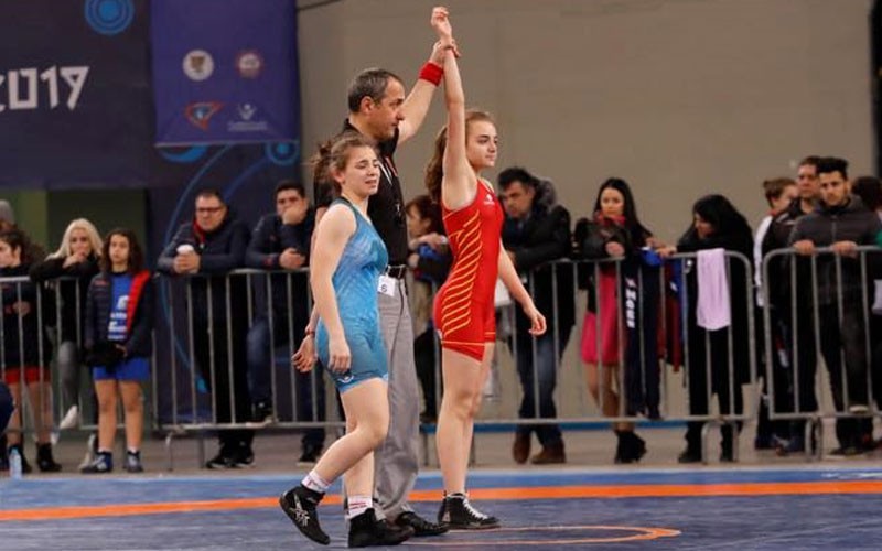 Dos luchadoras junto a un árbitro en la Acrópolis Cup