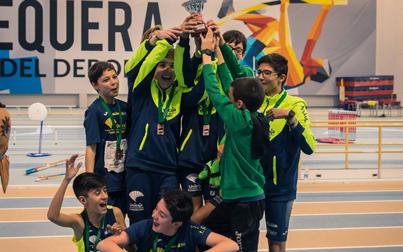 Atletas del Unicaja Atletismo levantando un trofeo