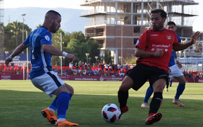 Un jugador del Linares pugna el balón con otro jugador de La Nucía